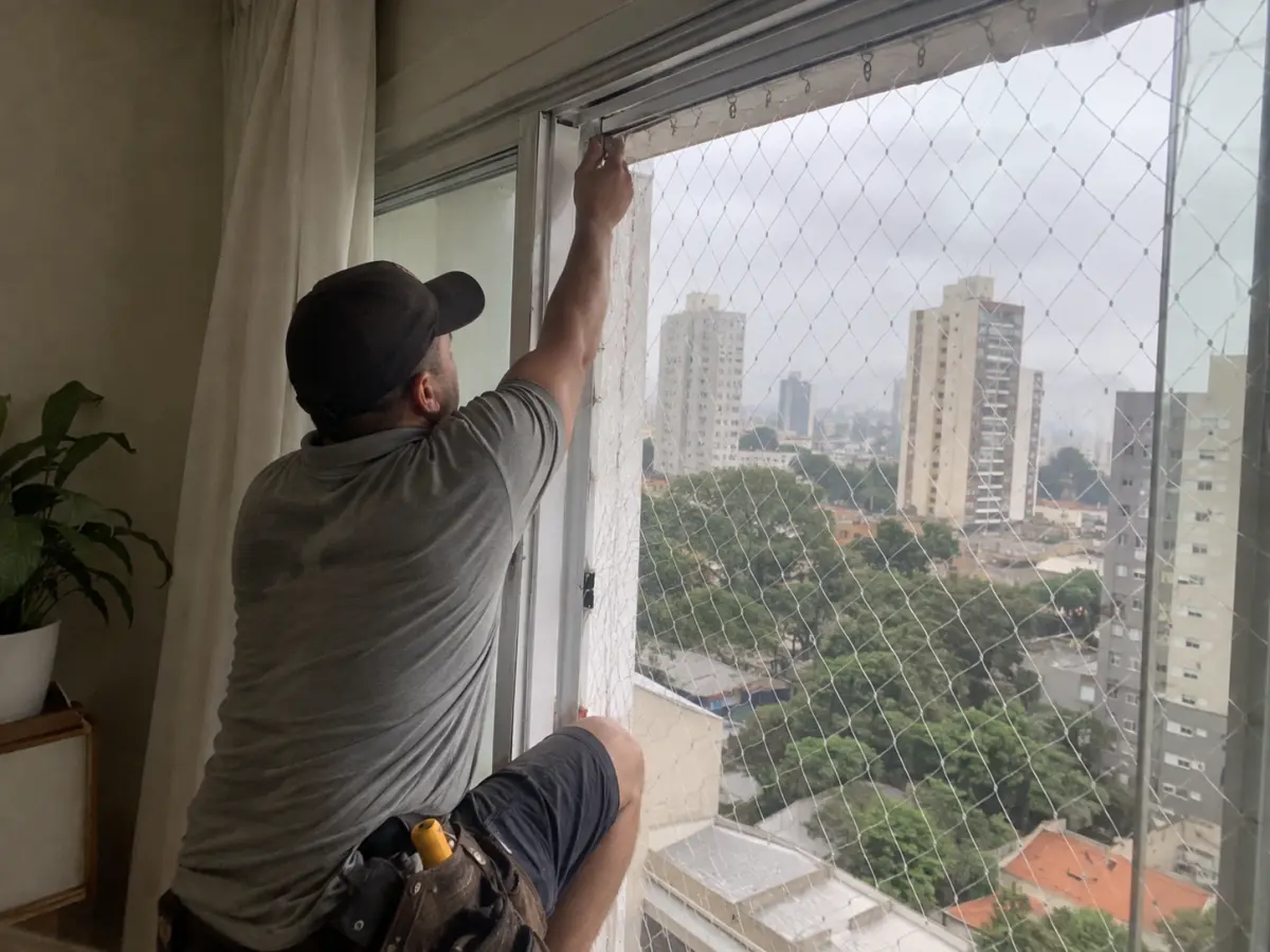 Instalador da GRU fixando rede de proteção em janela de apartamento em Guarulhos