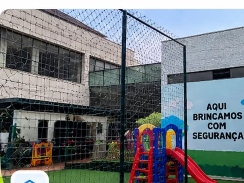 Mãe acompanhando criança em parquinho de condomínio cercado com tela de proteção