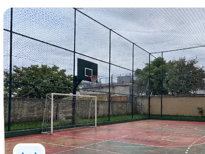 Jovens jogando bola em quadra cercada por tela de proteção esportiva